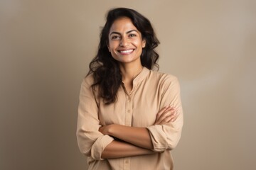 Portrait of a blissful indian woman in her 30s with arms crossed in front of light wood minimalistic setup