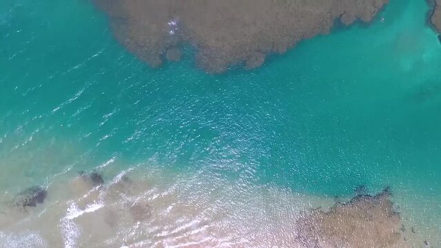 Praia paradis&iacute;aca no litoral do nordeste. V&iacute;deo de drone sobrevoando os corais no mar de Taipu de Fora, praia na Bahia, Brasil. Imagem a&eacute;rea mostrando turistas aproveitando a natureza.