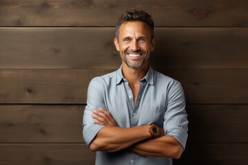 Portrait of a smiling man in his 40s with arms crossed isolated on light wood minimalistic setup
