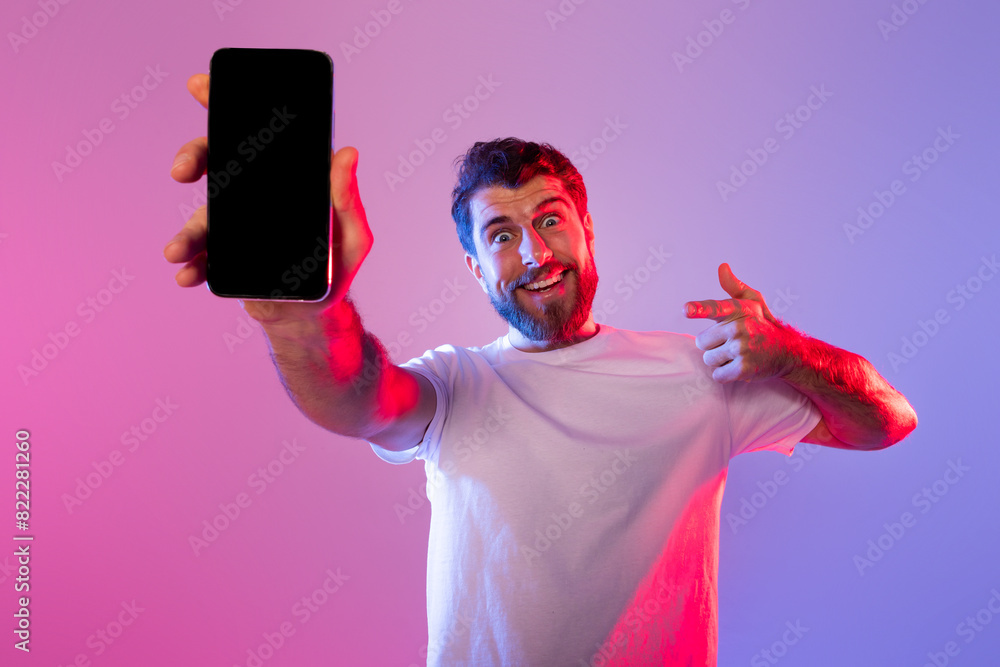 Poster A man wearing a white shirt is standing while holding a cell phone in his hand. He appears to be looking at the screen of the phone with a focused expression, mockup