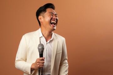 Naklejka premium Portrait of a grinning asian man in his 40s dancing and singing song in microphone in light wood minimalistic setup