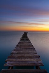 Obraz premium sunrise seascape with an old wooden dock leading out into the calm ocean waters