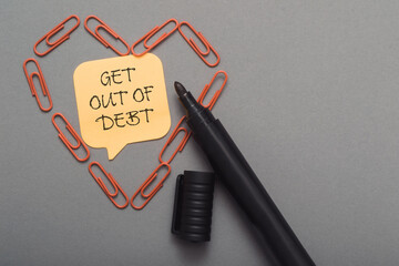 A pen with a note on it that says Get out of debt