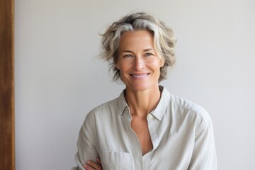 Fototapeta premium Portrait of a satisfied woman in her 50s smiling at the camera over light wood minimalistic setup