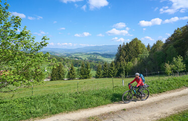 active senior woman on a bike packing tour with her electric mountain bike in the Bavarian Forest...