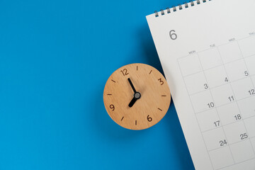 close up of clock and calendar on the blue table background, planning for business meeting or travel planning concept