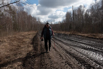 spring landscape with muddy swamp, forest road, spring, lonely traveler on a dirty wet road
