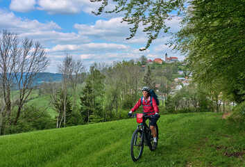 Naklejka premium active senior woman on a bike packing tour with her electric mountain bike in the Bavarian Forest near Wollaberg, Bavaria, Germany