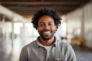 Portrait of a happy afro-american man in his 30s smiling at the camera on empty modern loft background