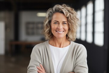Fototapeta premium Portrait of a satisfied woman in her 40s smiling at the camera over empty modern loft background