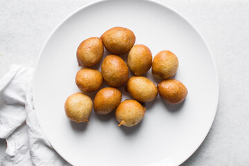 Overhead view of nigerian puff-puff on a white plate, nigerian fried dough balls, flatlay of homemade bofrot on white dish