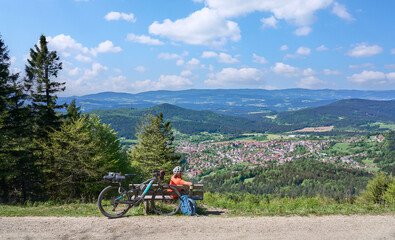 active senior woman on a bike packing tour with her electric mountain bikeup to the summit of Great Arber above village of  Bodenmais in the Bavarian Forest, Bavaria, Germany