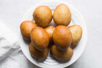 Overhead view of nigerian puff-puff on a white plate, nigerian fried dough balls, flatlay of homemade bofrot on white dish