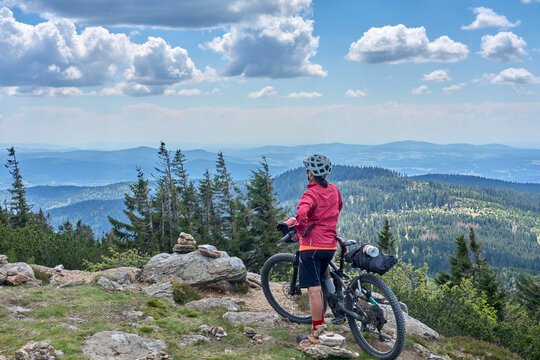 active senior woman on a bike packing tour with her electric mountain bike in the rocky  the summit of Great Arber in the Bavarian Forest, Bavaria, Germany