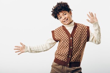 Young african american boy wearing a sweater vest, looking confident and stylish while posing on a simple white background