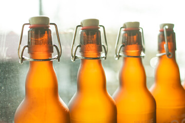 Brown beer bottles with bugle plug stand in a row by the window