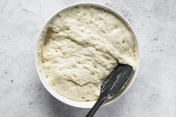 Overhead view of nigerian puff-puff dough that has proofed, puff-puff dough in a white mixing bowl,...