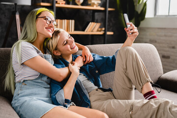 Happy caucasian young female lgbtq lesbian couple hugging cuddling together taking selfie on smart...