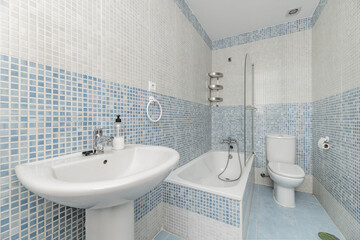 A bathroom with blue gresité-type tiles and white porcelain toilets