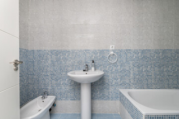 A bathroom with combined blue and white gresité-type tiles, white wooden doors and white porcelain...