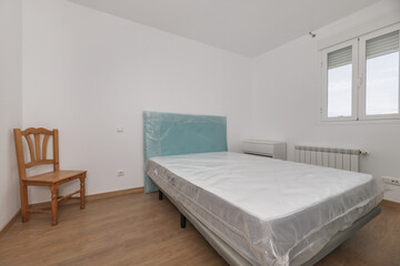 Bedroom with uninstalled bed with the protective plastics on