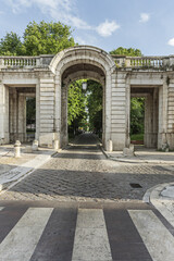 A cobblestone road passing under a vintage building with arches and passages