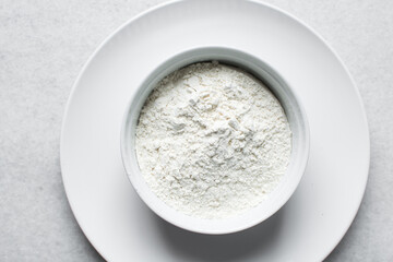 overhead view of All purpose flour in a white bowl, flatlay of baking flour in a white ceramic  bowl