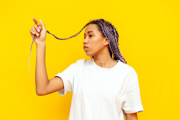 young african american woman with dreadlocks pointing with hand up on yellow isolated background,...
