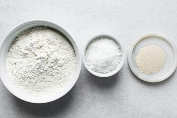 Overhead view of mise en place of ingredients for making nigerian puff-puff, flatlay of flour yeast sugar for puff-puff on a marble countertop, process of making puff-puff or bofrot