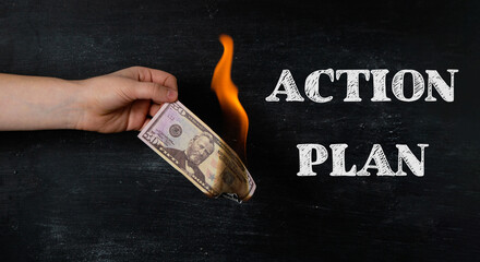 A hand holding a burnt dollar bill with the words Action Plan written below it