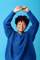A joyful young african american boy wearing a blue sweater expressing love by forming a heart with his hands