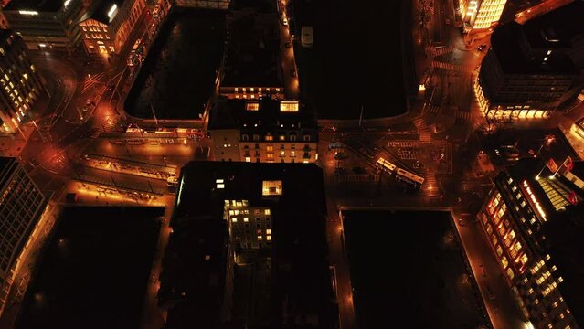 Captivating aerial night view of Geneva's l'Ile island on Rhine River, showcasing illuminated urban streets with buildings and flowing traffic