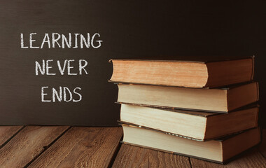 A stack of books with the words learning never ends written on a chalkboard