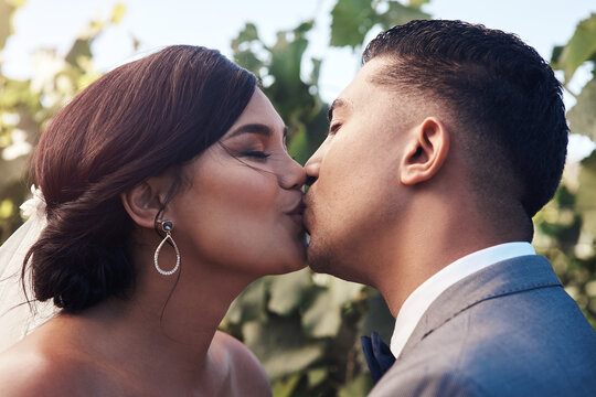 Couple, outdoor and kiss on wedding for love, commitment and promise for affection or emotional connection with care. Man, woman and intimate for celebration in garden for unity, safety and security.