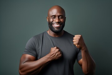 Obraz premium Portrait of a happy afro-american man in his 40s showing a thumb up while standing against bare monochromatic room