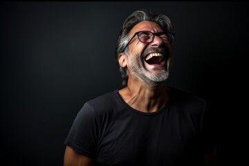 Naklejka premium Portrait of a glad man in his 50s laughing in front of bare monochromatic room