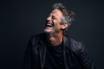 Obraz premium Portrait of a smiling man in his 50s laughing over bare monochromatic room