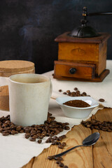 Still life of a cup of coffe sitting in the medium ground on a heap of roasted coffee beans, with a...