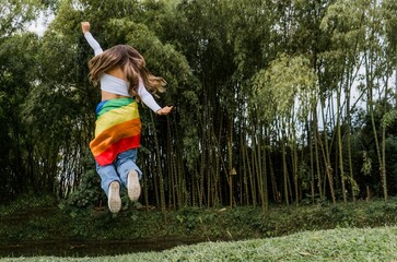 joven mujer al aire libre y la bandera del orgullo gay en su cintura saltando de felicidad 