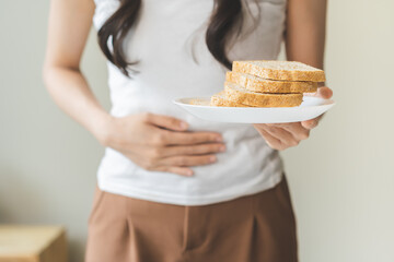 Gluten allergy, asian young woman hand holding, refusing to eat white bread slice on plate in...