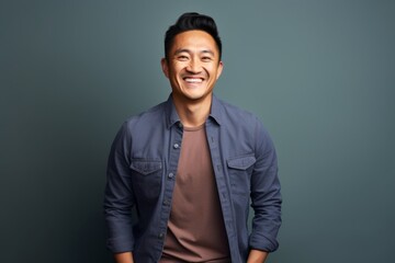 Fototapeta premium Portrait of a joyful asian man in his 30s smiling at the camera isolated on plain cyclorama studio wall