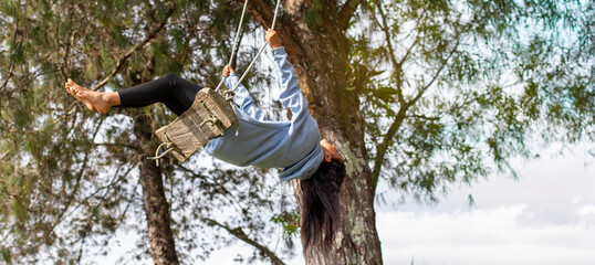lifestyle: latina woman swings on a swing in a tree