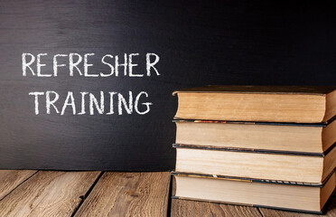 A stack of books with the word refresher training written on a chalkboard