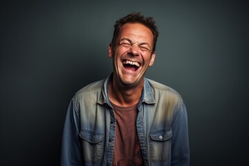 Fototapeta premium Portrait of a glad man in his 40s laughing over plain cyclorama studio wall