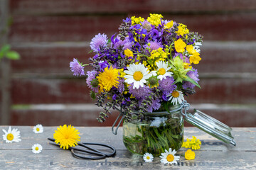 Blumenstrauß mit gelben und lila Wiesenblumen im Glas