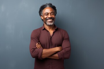 Obraz premium Portrait of a satisfied afro-american man in his 50s with arms crossed in plain cyclorama studio wall