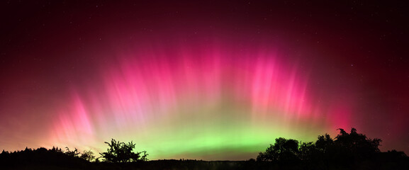 Fascinating Northern Lights over Central Europe. Vibrant Aurora Borealis in pink and green arch...