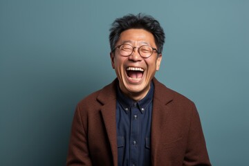 Portrait of a happy asian man in his 80s laughing in plain cyclorama studio wall