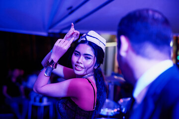 Music, dancing and Asian woman in nightclub with lights at disco event, celebration or concert. Happy, neon and female person moving to techno song with dj at rave or party for nightlife in Thailand.