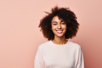 Portrait of a blissful afro-american woman in her 20s smiling at the camera in plain cyclorama studio wall